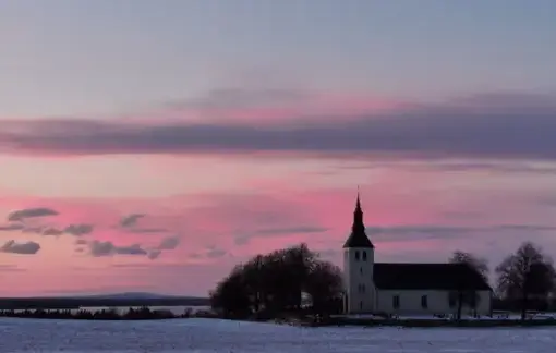 Utsikt mot Gudhems kyrka och klosterruin med Kinnekulle i bakgrunden