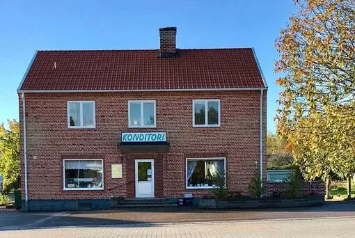 Fasaden av Conditori Lifweni med en röd tegelbyggnad och skylten "Konditori."