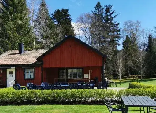 Kaffestugan i Alphems Arboretum, en charmig röd byggnad med sittplatser utomhus.