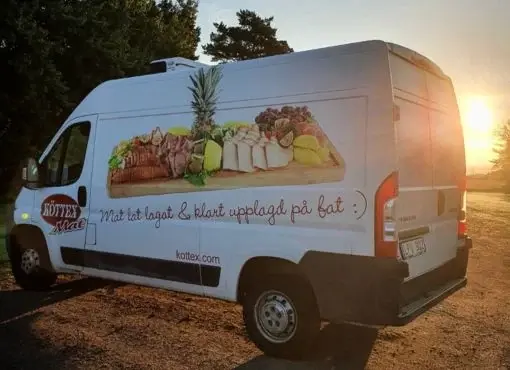 Köttex Mat-leveransbil med reklam för catering och exotiska plankor, fotograferad vid solnedgång.