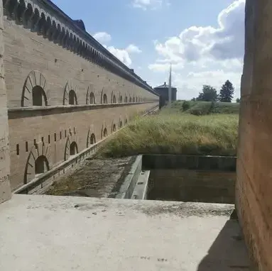 Utsikt över Karlsborgs fästnings murar En blick ut genom ett fönster över fästningens murar och det omkringliggande landskapet.