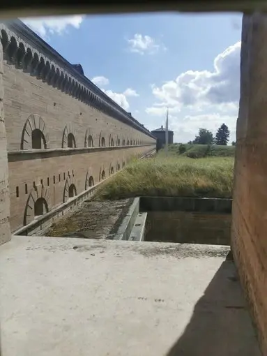 Utsikt över Karlsborgs fästnings murar En blick ut genom ett fönster över fästningens murar och det omkringliggande landskapet.