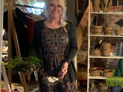 Marina Bonnevier står i sin butik omgiven av keramik och hantverk, håller ett keramikföremål i händerna.