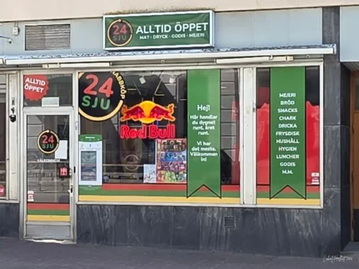Butiksfasad för 24 Sju i Falköping med skyltning för snacks, godis, dryck och vardagsvaror.
