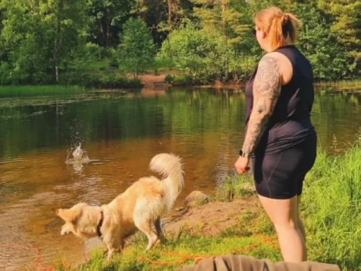 Hund badar vid Femöringen nära Edsvära medan en person står vid strandkanten.