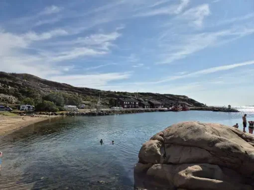 Badande vid sandstrand och klippor i Fiskebäcksvik i Lysekil.