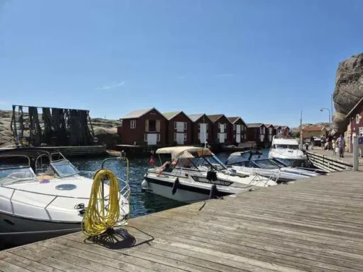 Hamnen och sjöbodarna på Smögen Båtar i hamnen och rad av röda sjöbodar längs Smögenbryggan.